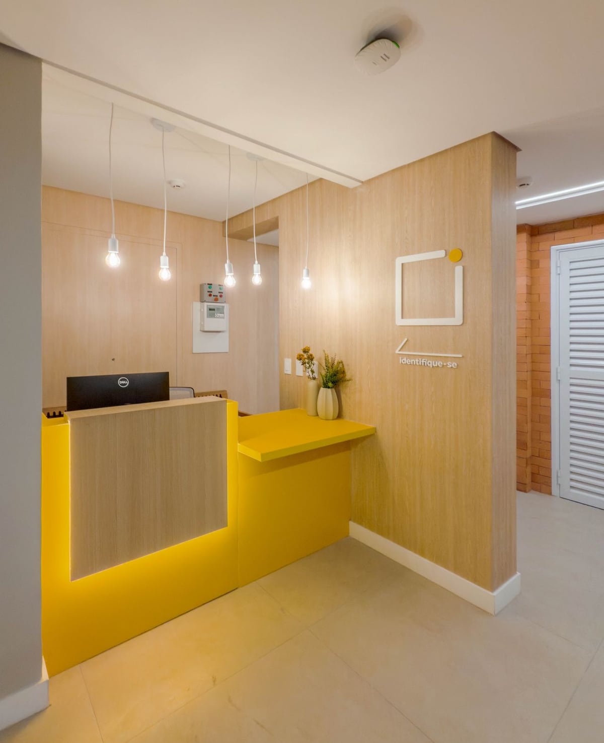 Recepção do espaço clínico, com balcão de atendimento e iluminação pendente.